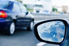 young man driving a car reflected in the wing mirror